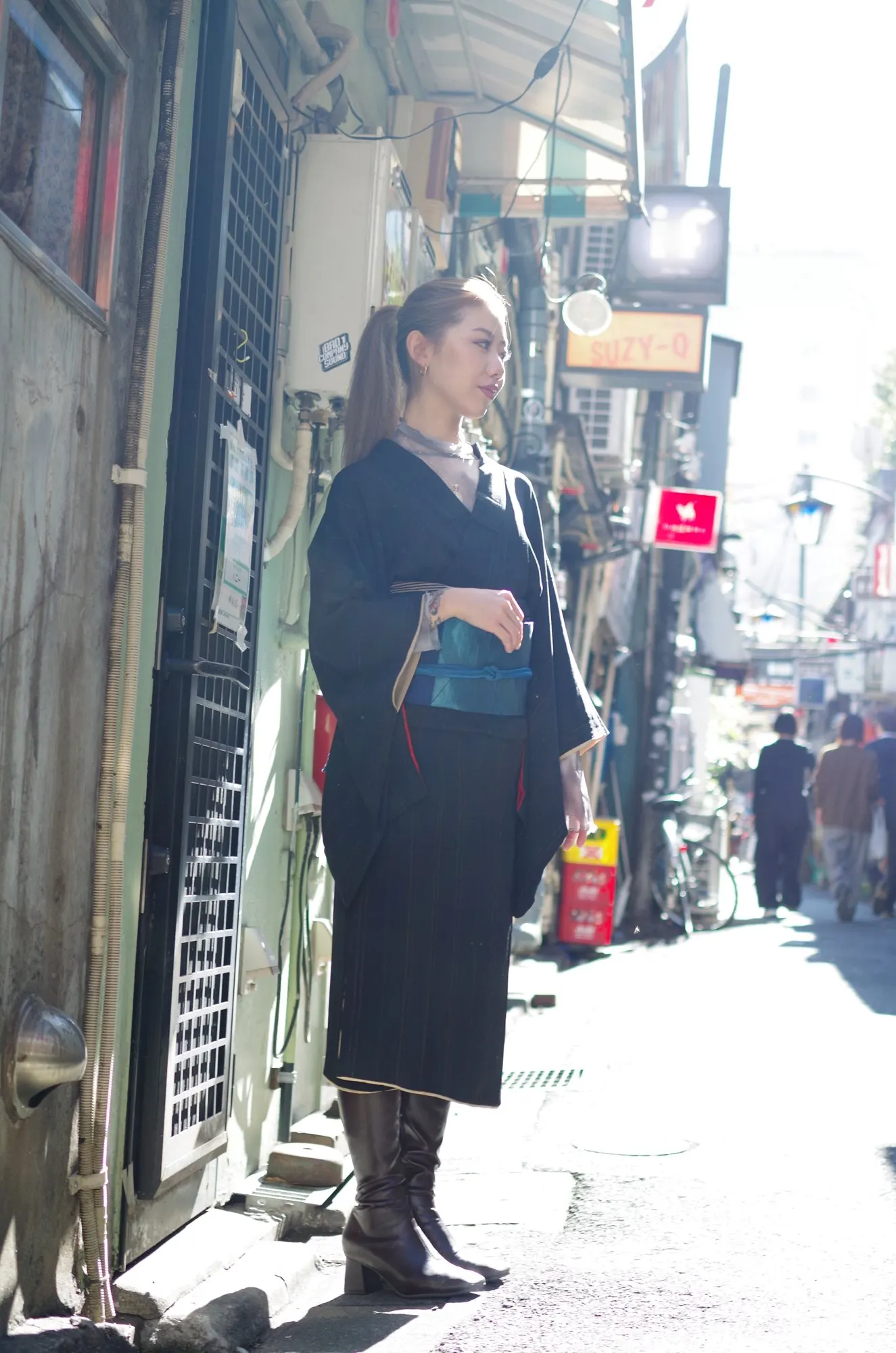 路地に立つ黒い着物とブーツのコーディネート