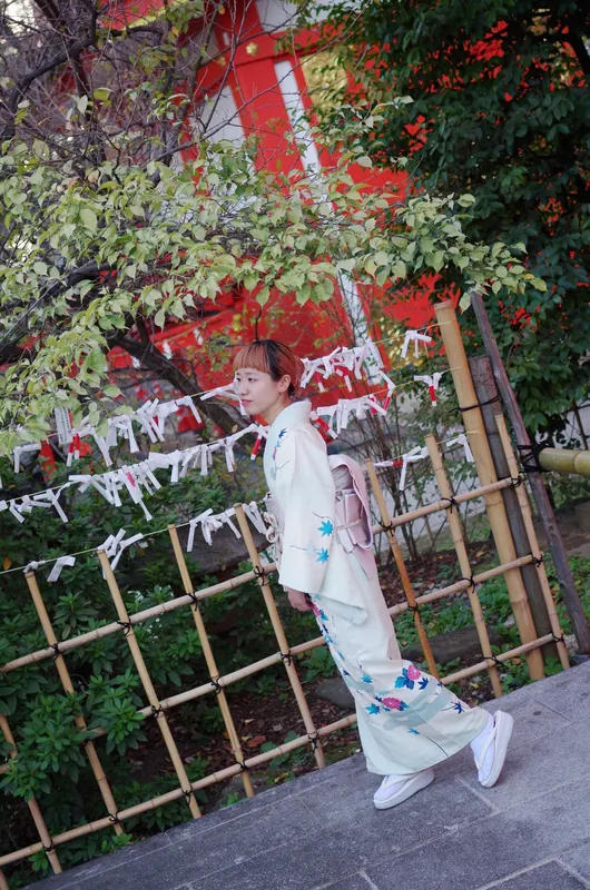 神社の境内を歩く淡い色の着物姿